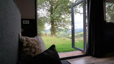 a room with a window with a view of a field at Little Acorn - Luxury shepherd's hut / lodge with private hot tub and garden in Llanfyllin
