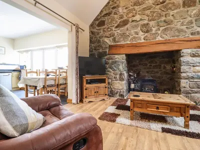 a living room with a stone fireplace and a couch at Caerffynon Bach in Dyffryn