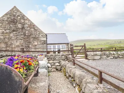 a house with a stone wall and flowers in a yard at Caerffynon Bach in Dyffryn