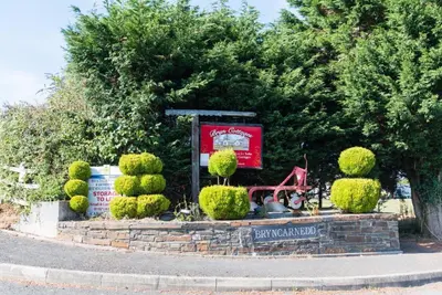 a sign in a garden with bushes and trees at The Calf Suite in Aberystwyth