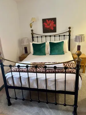a bedroom with a bed with a black frame and green pillows at The Calf Suite in Aberystwyth
