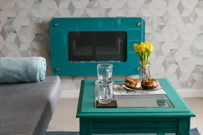 a green coffee table with a vase of flowers on it at Finest Retreats - Golygfa o'r Castell - Castle Views in Harlech
