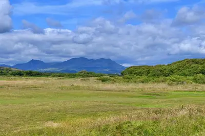 a field of grass with mountains in the background at Finest Retreats - Golygfa o'r Castell - Castle Views in Harlech
