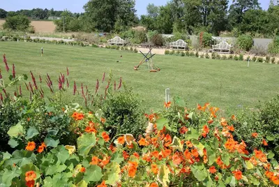 a garden with orange flowers and a field of grass at Garden Cottage at Eaton Manor in Eaton