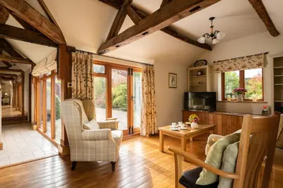 a living room with wooden floors and wooden beams at Garden Cottage at Eaton Manor in Eaton