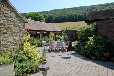 a patio with a table and chairs in a garden at Garden Cottage at Eaton Manor in Eaton