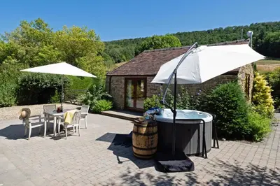 a hot tub with an umbrella and a table at Garden Cottage at Eaton Manor in Eaton