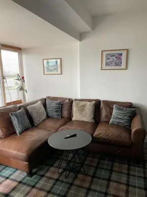 a brown couch in a living room with a table at Ty Bach in Aberystwyth