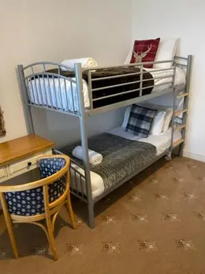 a room with two bunk beds with a desk and a chair at Ty Bach in Aberystwyth