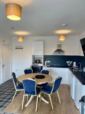 a kitchen with a wooden table and blue chairs at Ty Bach in Aberystwyth