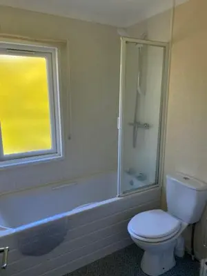 a bathroom with a toilet and a shower and a window at Lodges at Bryncarnedd, Aberystwyth in Aberystwyth