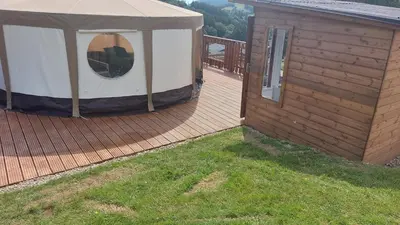 a gazebo on a deck next to a house at Yurt Uchaf Off-Grid Glamping in Machynlleth