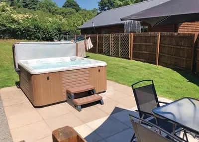 a hot tub in a yard with a chair at Heartsease Lodges in Llanddewi Ystradenny