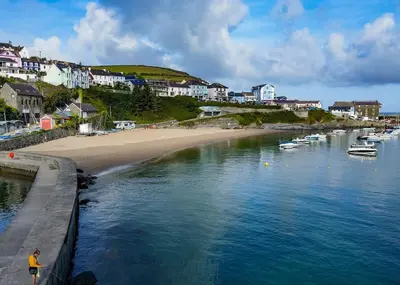 a man standing on a wall near a beach with boats at Seven Springs in Llanon