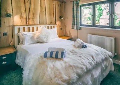 a bedroom with a large white bed with towels on it at The Warrens At Foxtail in Chirk