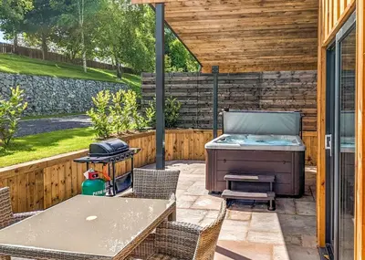 a patio with a grill and a table and chairs at The Warrens At Foxtail in Chirk
