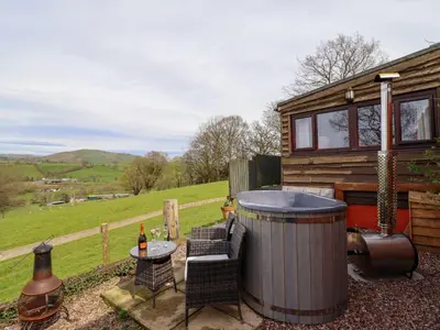 a tiny house with a hot tub and a table and chairs at The Retreat in Oswestry