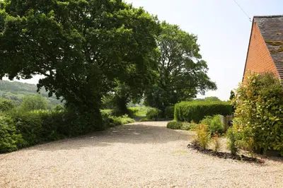 a gravel driveway with a tree and a house at Woodpecker Way at Eaton Manor in Eaton