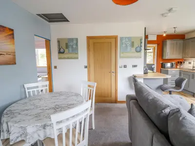 a kitchen and a living room with a table and a couch at Bryn Hyfryd in Talsarnau