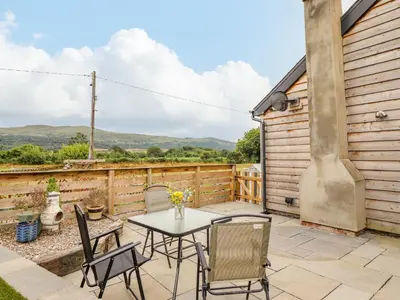a patio with a table and chairs and a view at Bryn Hyfryd in Talsarnau