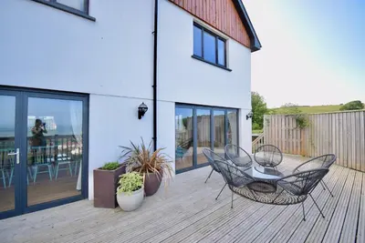 a patio with two chairs and a table on a deck at Ty Ni in New Quay
