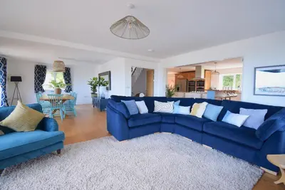 a living room with blue couches and a table at Ty Ni in New Quay