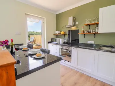 a kitchen with a counter with a table with glasses of wine at Cam O'r Fechan Annexe in Llangollen