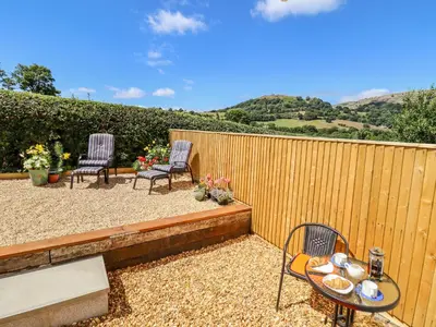 a patio with two chairs and a table and a fence at Cam O'r Fechan Annexe in Llangollen