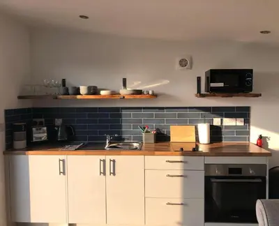 a kitchen with white cabinets and a sink and a microwave at MAESLLAN CABINS - 'Golwg Y Mor' in Cross Inn