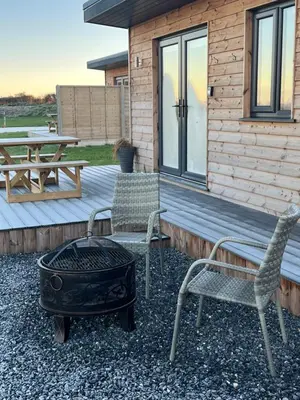 two chairs and a grill in front of a cabin at MAESLLAN CABINS - 'Golwg Y Mor' in Cross Inn