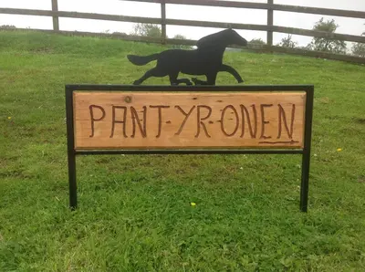 a sign with a dog statue on top of it at Pant yr onen holidays in Llandrindod Wells