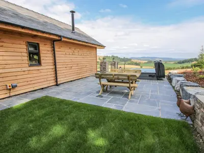 a patio with a picnic table next to a building at Llety Cariad in Montgomery