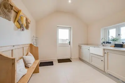 a kitchen with white cabinets and a wooden bench at 3 Bed in Trawsfynydd oc-wag718 in Trawsfynydd