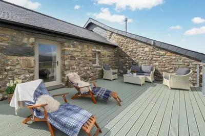 a deck with rocking chairs and a stone building at 3 Bed in Trawsfynydd oc-wag718 in Trawsfynydd