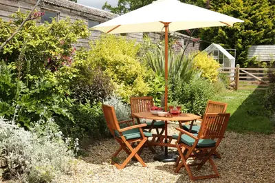a table and chairs with an umbrella in a garden at Great Western Lodge at Eaton Manor in Eaton
