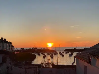 a sunset over a harbor with boats in the water at Aberaeron Island House - Panoramic Harbour Views in Aberaeron