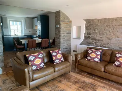 a living room with two leather couches and a kitchen at Aberaeron Island House - Panoramic Harbour Views in Aberaeron