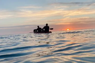 two people sitting on a boat in the water at Aberaeron Island House - Panoramic Harbour Views in Aberaeron
