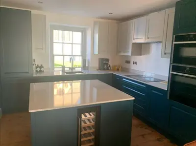 a kitchen with blue cabinets and a white counter top at Aberaeron Island House - Panoramic Harbour Views in Aberaeron
