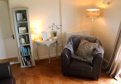 a living room with a chair and a table with a lamp at Mortimer Trail B and B in Aymestrey