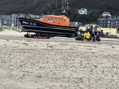 a boat on the back of a truck on the beach at Harbour Apartment in Barmouth