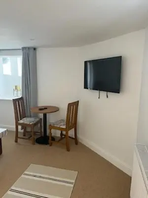 a living room with a table and a tv on the wall at Harbour Apartment in Barmouth