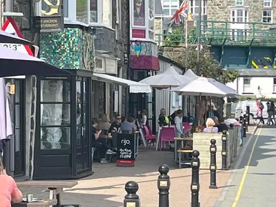 a group of people sitting at tables on a city street at Harbour Apartment in Barmouth
