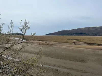 an empty road in a field with mountains in the background at Harbour Apartment in Barmouth