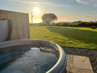 a bath tub filled with water in a yard at MAESLLAN CABINS 'Hud Y Machlud' in Cross Inn