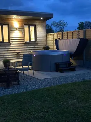a backyard with a hot tub next to a house at MAESLLAN CABINS 'Hud Y Machlud' in Cross Inn