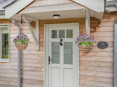 a front door of a house with two baskets of flowers at Violet Cottage in Hereford