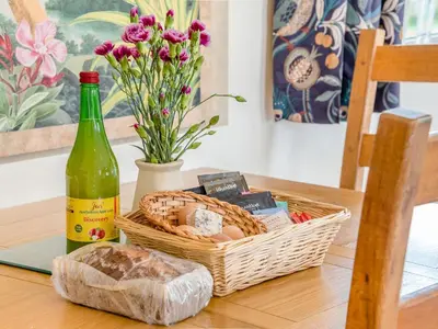 a basket of bread and a bottle of wine on a table at Violet Cottage in Hereford