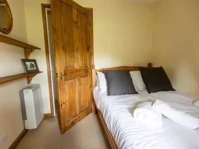 a bedroom with a bed and a wooden door at Cosy cottage with views over the Shropshire hills - Pass the Keys in Ludlow