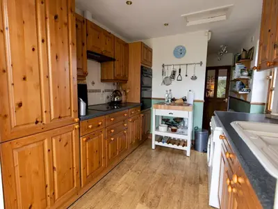 a large kitchen with wooden cabinets and a sink at Cosy cottage with views over the Shropshire hills - Pass the Keys in Ludlow